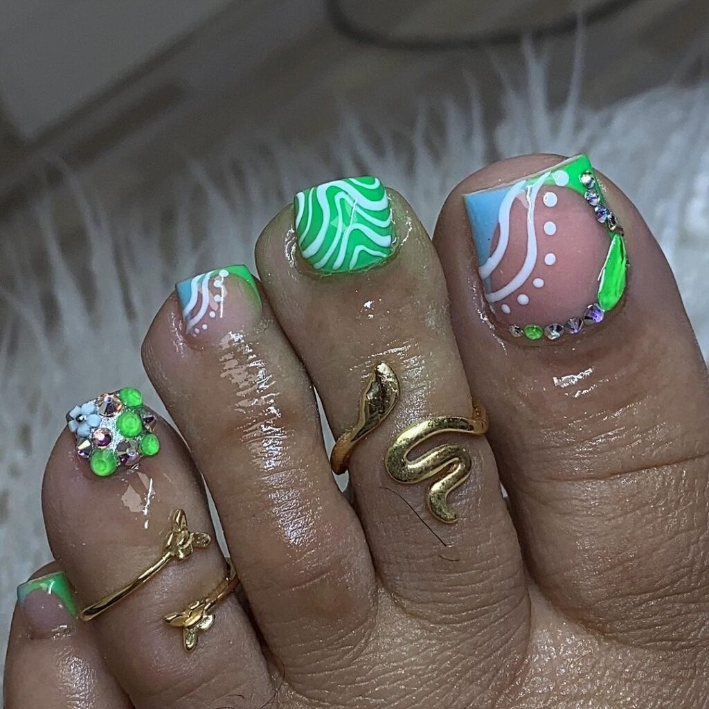 Las uñas de los pies de una mujer están decoradas con diseños verdes y blancos.