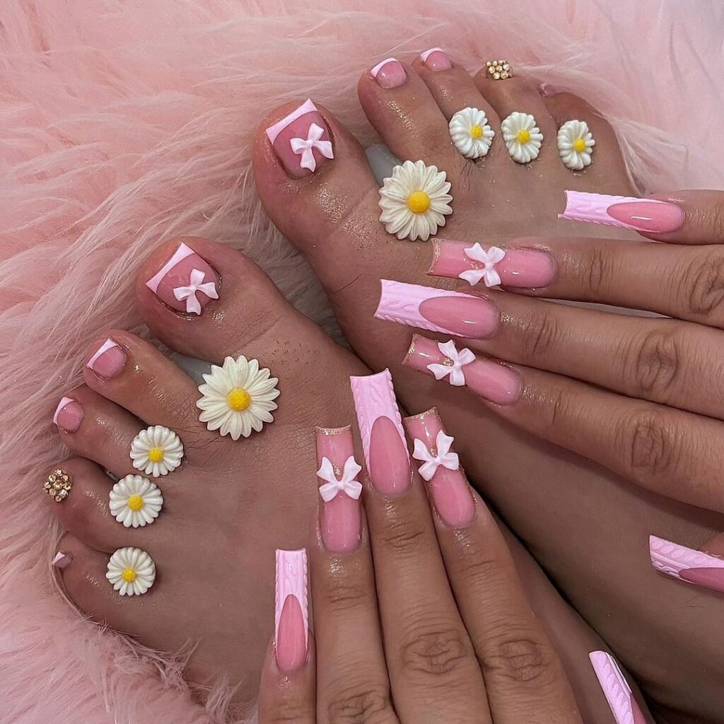 Las uñas rosadas de los pies de una mujer con margaritas.