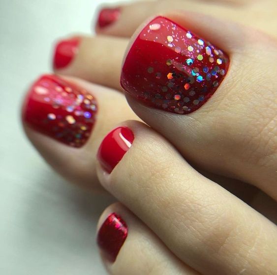 Los dedos de los pies de una mujer con brillo rojo.