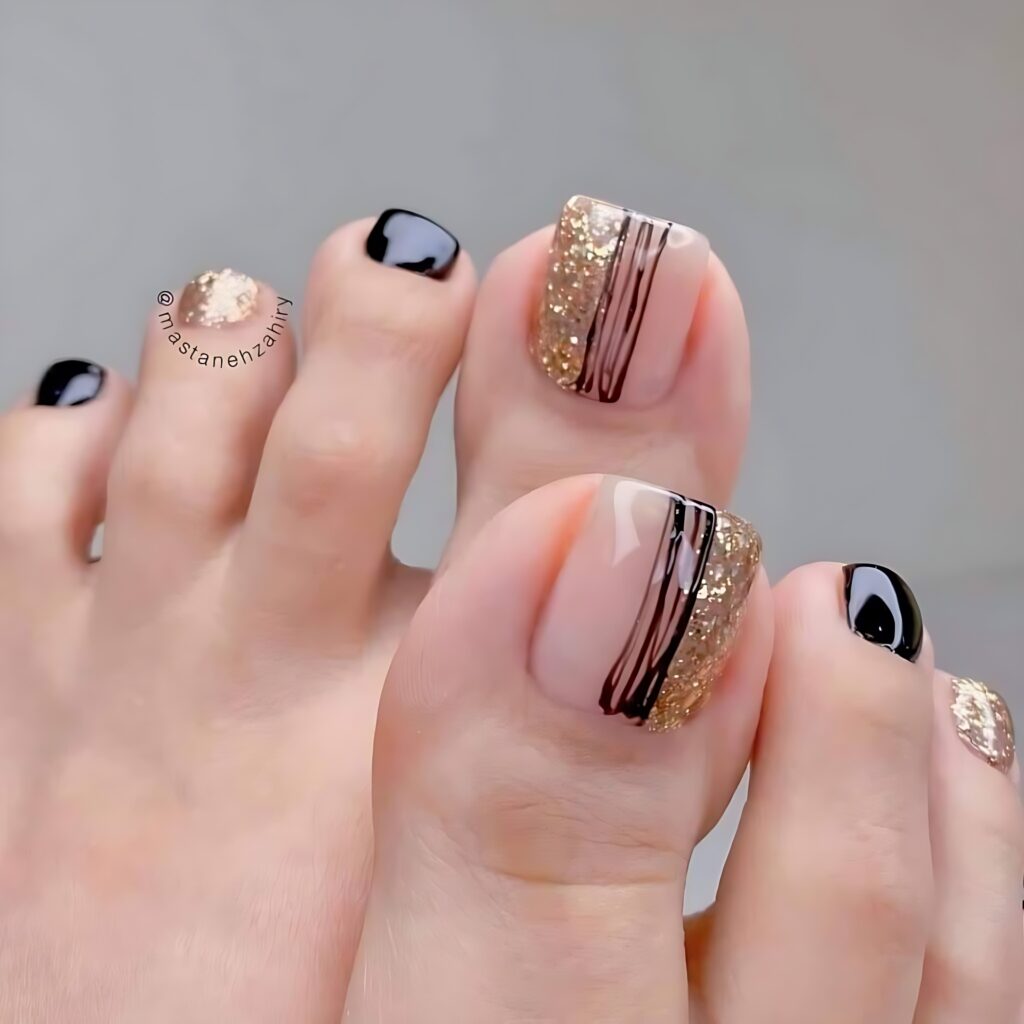 Los dedos de los pies de una mujer con diseños de uñas negras y doradas.