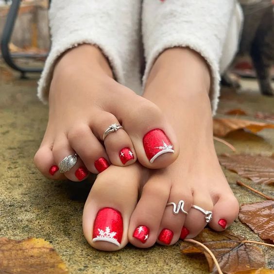Los dedos de los pies de una mujer con esmalte de uñas rojo y un anillo de plata.