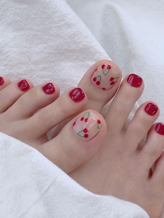 Los pies de una mujer con esmalte de uñas rojo y flores.