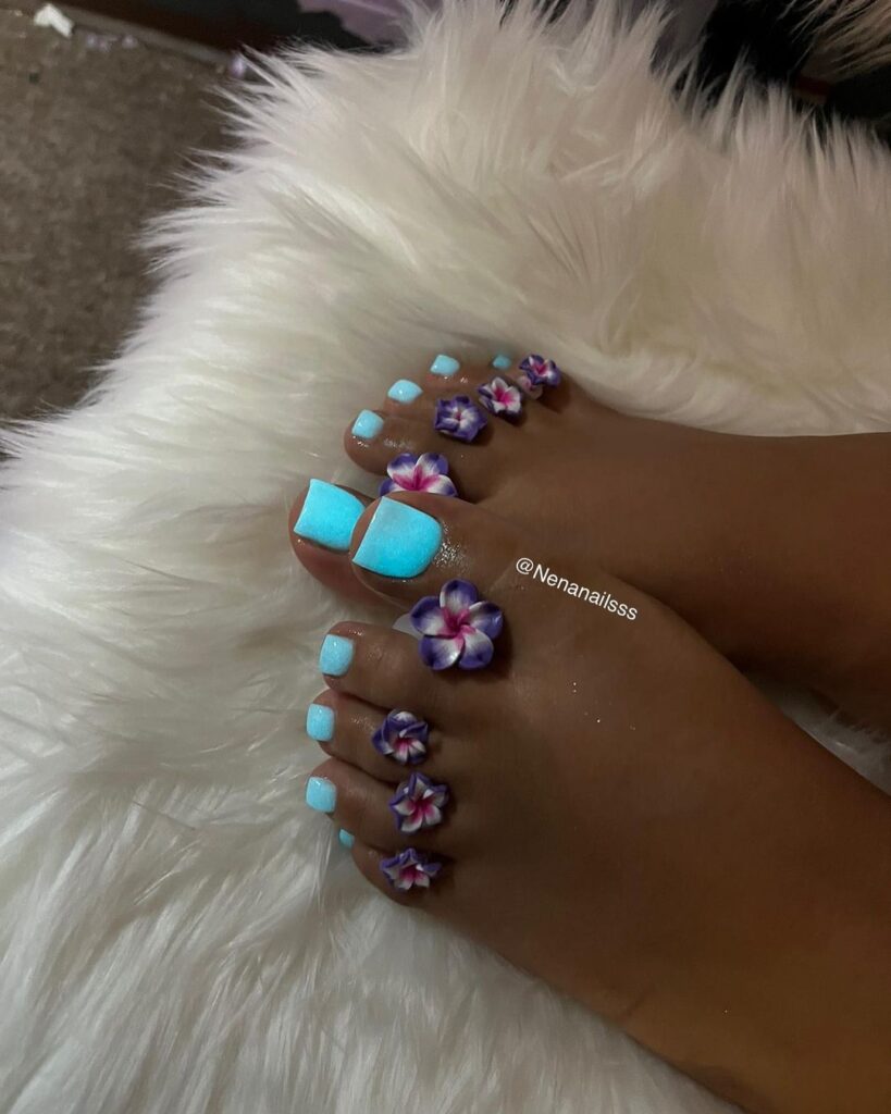 Los pies de una mujer con uñas azules y moradas.