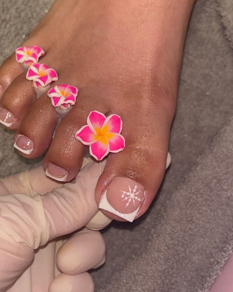 Una mujer a la que le pintan los dedos de los pies con flores rosas.