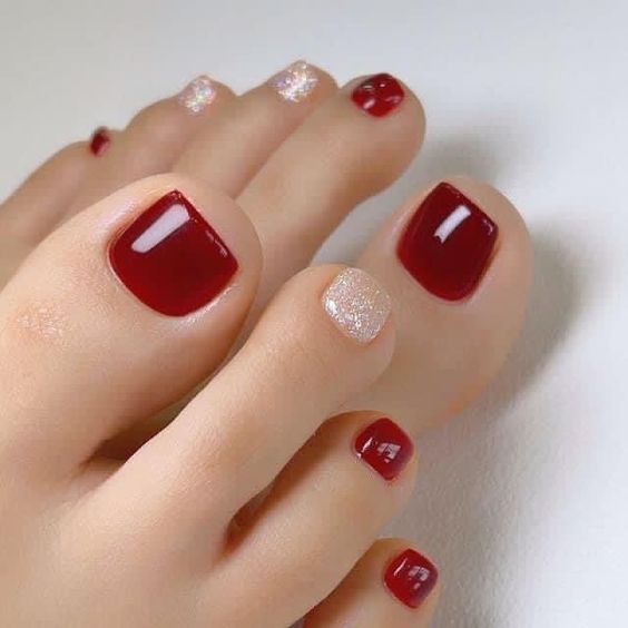 Una mujer con los pies decorados con uñas rojas y blancas.